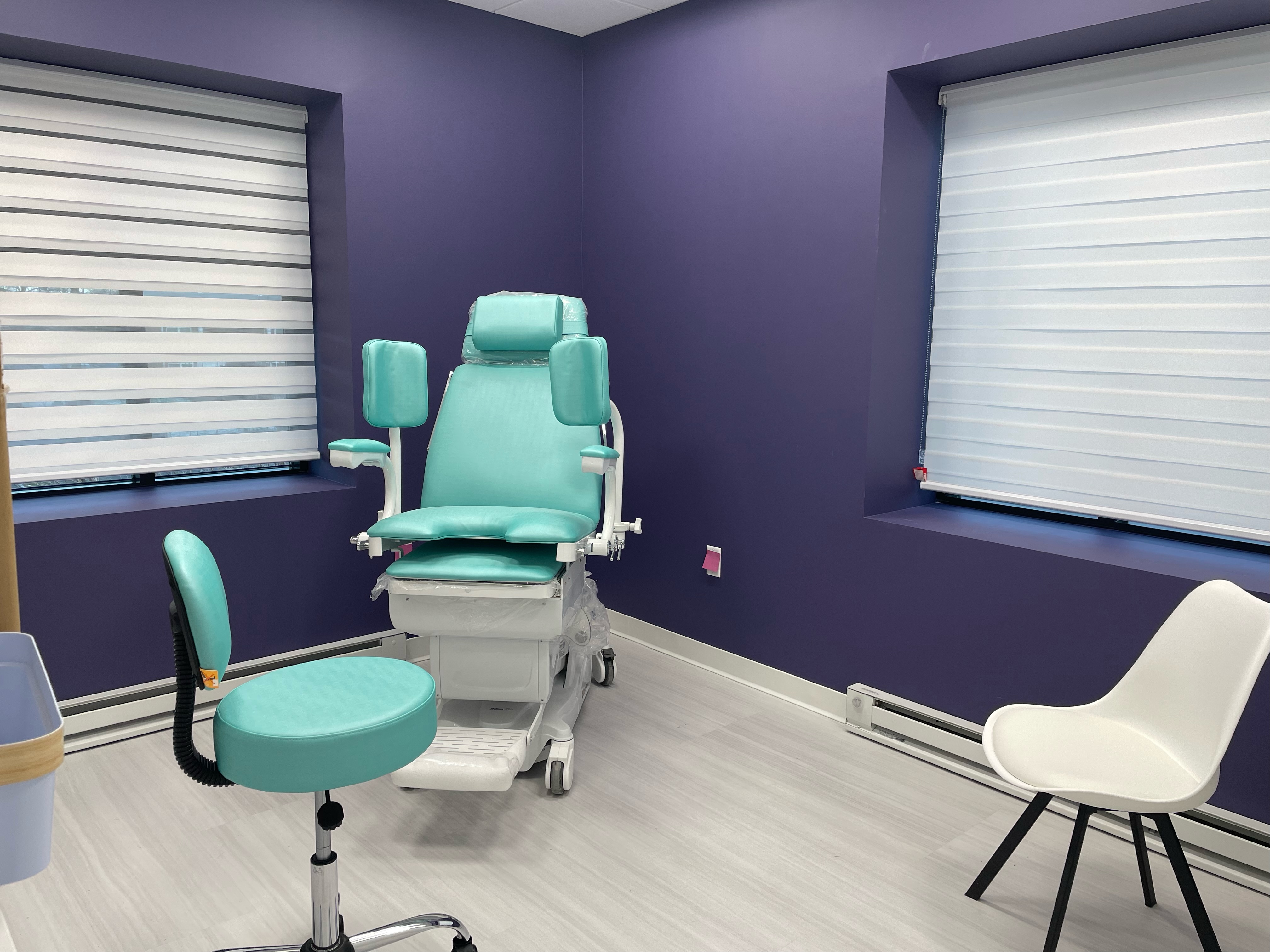 Empty medical room with one operating chair and one swiveling chair and one sitting chair